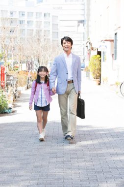 Japon baba ve kızı sokakta yürüyor.