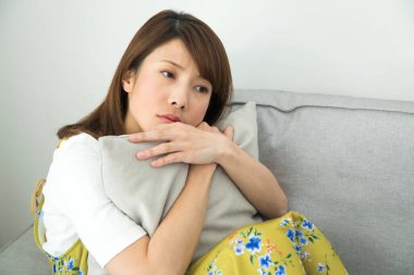 Üzgün kadın kanepede oturuyor.