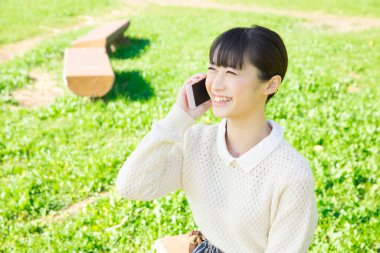 Açık havada akıllı telefonları olan Japon bir kızın portresi.