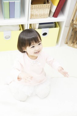 Yerde oynayan Asyalı kız.