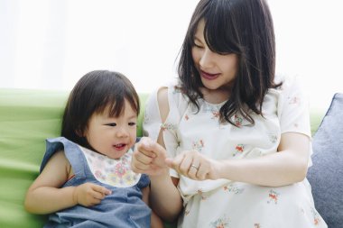 Evdeki oturma odasında annesiyle oynayan tatlı Asyalı küçük kız.