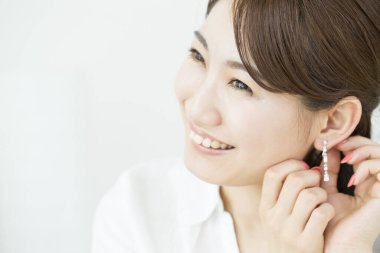 Beyaz arka planda küpe takan güzel bir Japon kadın. 