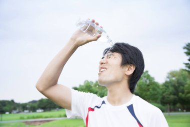 Asyalı adam parkta üzerine su döktü.