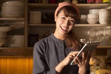Tabletli gülümseyen genç Asyalı şef kadın sipariş alıyor.