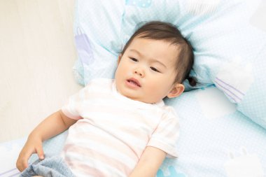 Küçük Asyalı bebek yatakta uzanıyor.