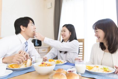 Üç kişilik Japon ailesi mutfakta kahvaltı yapıyor.