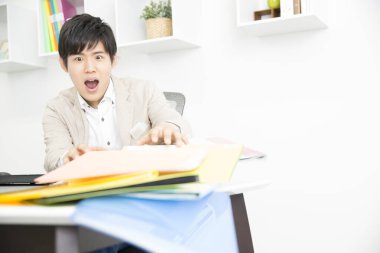 Masada bir sürü klasörle Asyalı genç öğrenci okuyor. 