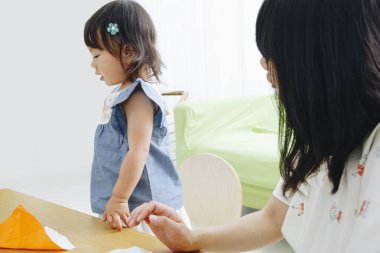 Küçük Asyalı kız evde annesiyle oynuyor.