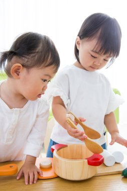 İki küçük Asyalı kız tahta oyuncaklarla oynuyorlar.