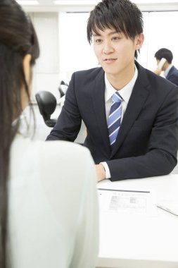 Genç Asyalı işadamı kadın müşteriyle birlikte çalışıyor.