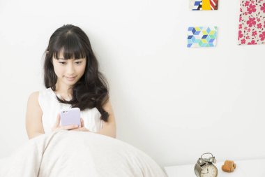 Kız yatak odasında akıllı telefon kullanıyor. 