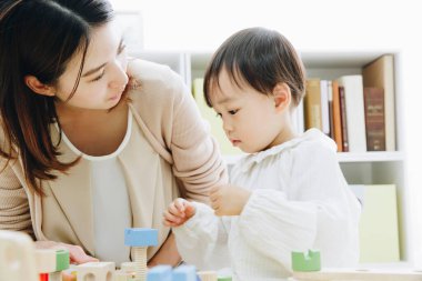 Asyalı anne ve küçük oğlu evde, yaşam tarzında ve aile kavramında oynuyorlar..