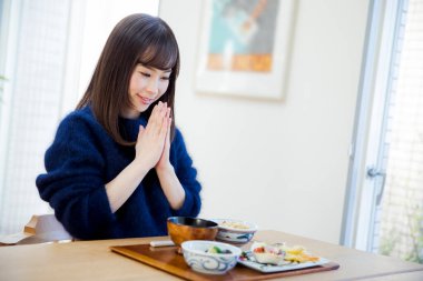 Asyalı kadın mutfakta kahvaltı yapıyor.