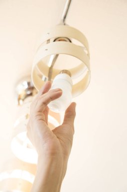 Avizedeki ampulü değiştiren elektrikçinin eli. 