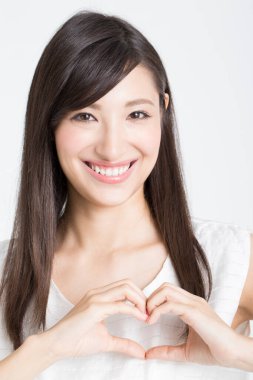 Genç, güzel Asyalı kadın, elleri beyaz arka planda izole bir şekilde duyma yeteneğini gösteriyor. 