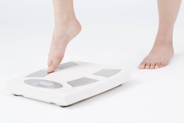 Kadın bacakları zemin terazisine basıyor, yakın plan. Terazinin üzerinde duran çıplak kadın, beyaz arkaplan