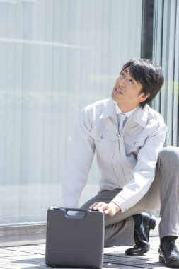 Sokakta alet çantası olan yakışıklı Asyalı bir işçi. 