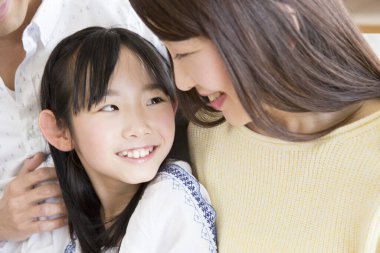 Kanepede çocuğu olan genç Asyalı bir aile. 