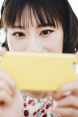 Asyalı kadın akıllı telefonuyla fotoğraf çekiyor. 