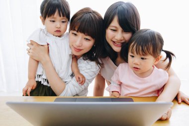 Evde dizüstü bilgisayar kullanan genç anneler ve çocuklar