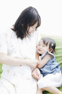 Asyalı anne ve küçük bebek kanepede oynuyor. 