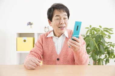 Ofiste cep telefonu kullanan Asyalı kıdemli bir adam. 