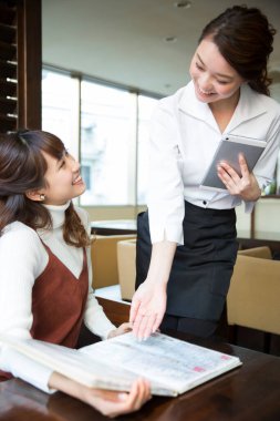 Güzel Japon garson restoranda tabletle sipariş veriyor.