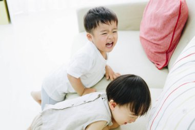 İki neşeli çocuk kanepede gülüyor.