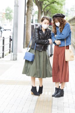 Arkadaşlarıyla şehirde maske takan genç bir kadın.