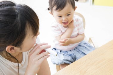 Kadın ve çocuk ahşap masada etkileşim halindeler.