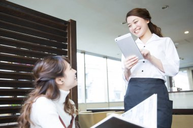 Güzel Japon garson restoranda tabletle sipariş veriyor.