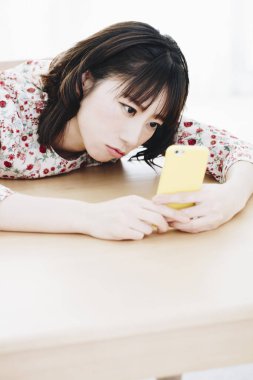 Evde akıllı telefon kullanan güzel bir Asyalı kadın.