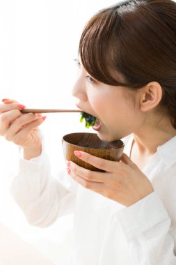 Genç Japon kadın çubuklarla yemek yiyor.