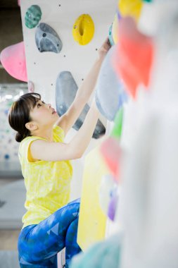 Güzel Japon kadın spor salonunda duvara tırmanıyor. 