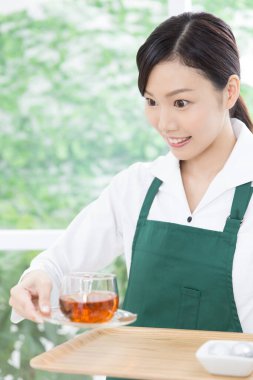 Genç Asyalı garson kafede çay servisi yapıyor.