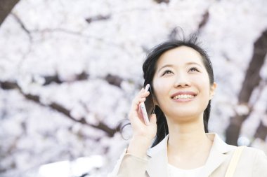 Parkta cep telefonu kullanan genç bir kadın.