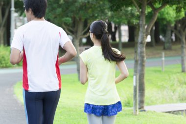 Sportif genç Asyalı çift parkta koşuyor.