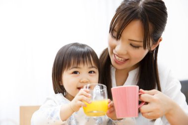 Anne ve kızı portakal suyu içiyorlar.