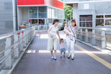 Dışarıda iki küçük çocukla yürüyen iki kadın.