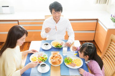 Mutlu Asyalı bir aile mutfakta kahvaltı yapıyor.