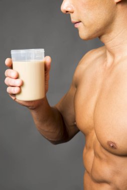 Genç kaslı adam protein içeceği tutuyor.