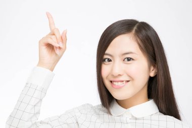 Güzel Japon kadının beyaz arka planı işaret ettiği bir stüdyo fotoğrafı. 