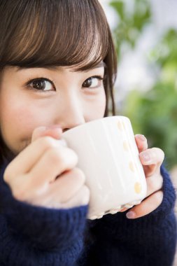 Kafede kahve içen genç Asyalı kadın.