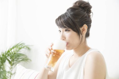 Genç Japon kadın elinde bira tutuyor.