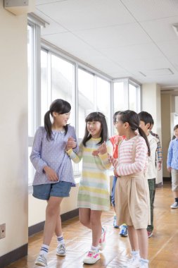 Çocuklar okul koridorunda mutlu bir şekilde konuşuyor.