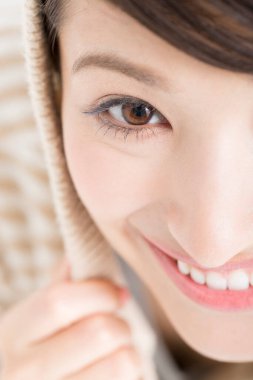 Güzel gülümseyen Asyalı kadın beyaz arka planda kapüşonlu süveter giyiyor..