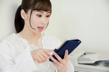 Ofiste akıllı telefon kullanan güzel Asyalı kadın.