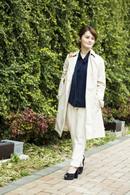 Paltolu güzel bir kadının parkta yürüdüğü uzun bir çekim. 