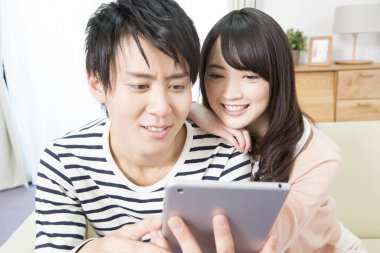 Mutlu Asyalı çift evde tablet kullanıyor.