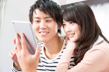 Mutlu Asyalı çift evde tablet kullanıyor.